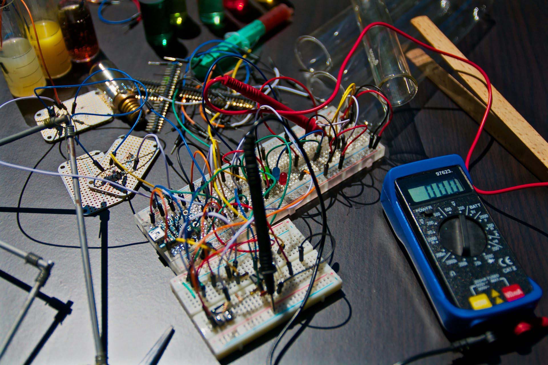 Messy electronic breadboard with wires and tools.