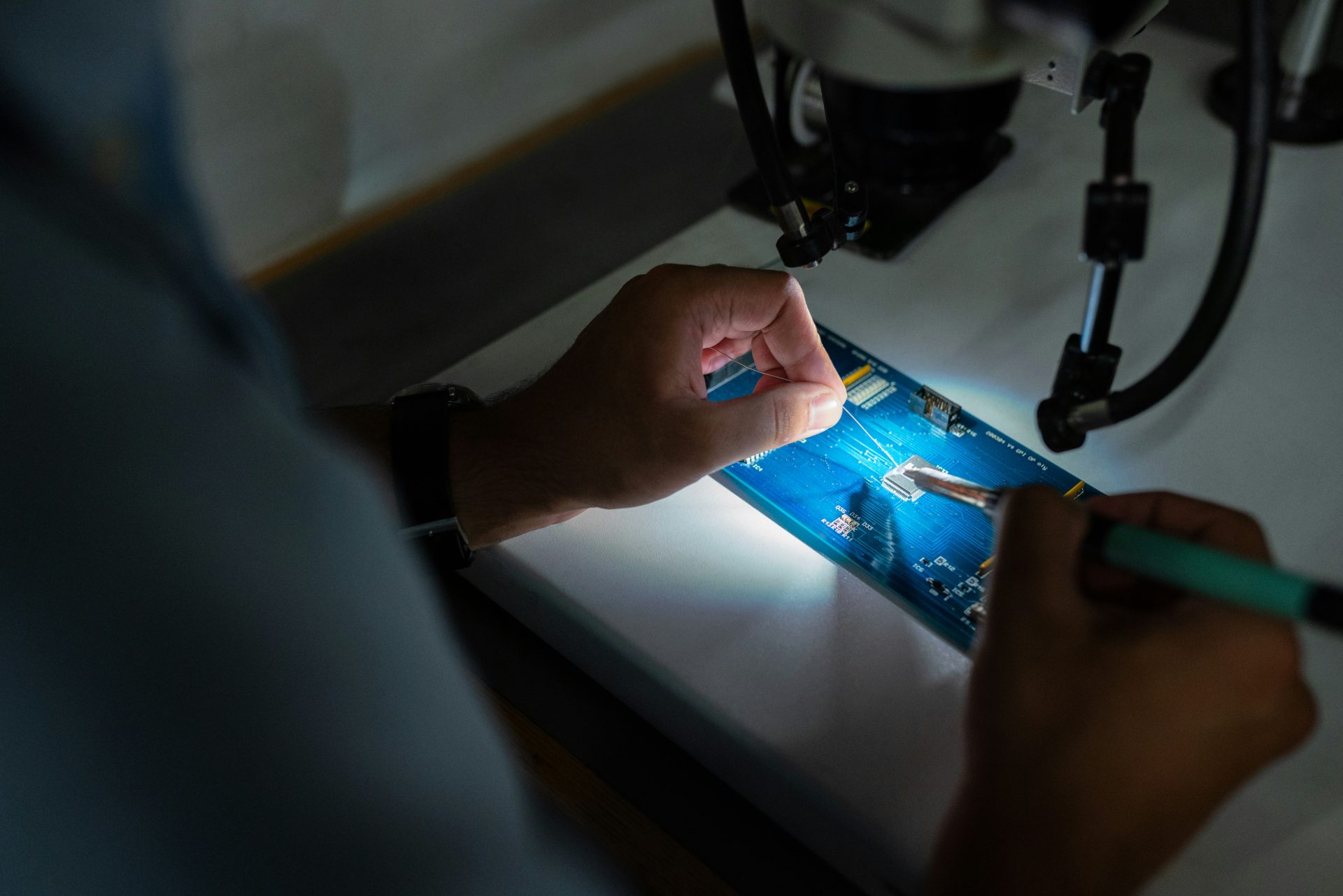 Technician soldering circuit board with precision.