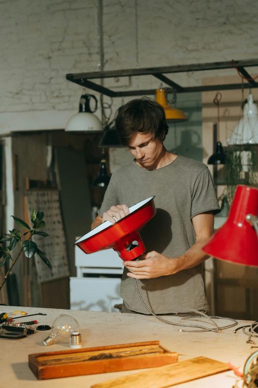 Man repairing a red lamp on table.